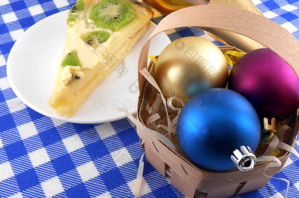 盘子、酒瓶和圣诞球旁的奇异果美味蛋糕