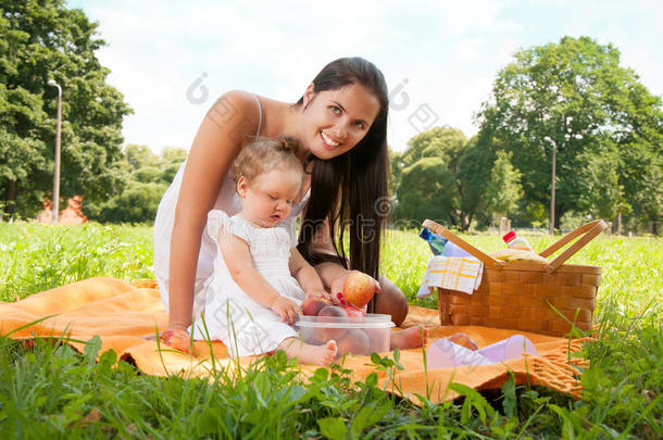 年轻快乐的妈妈带着女儿在公园野餐
