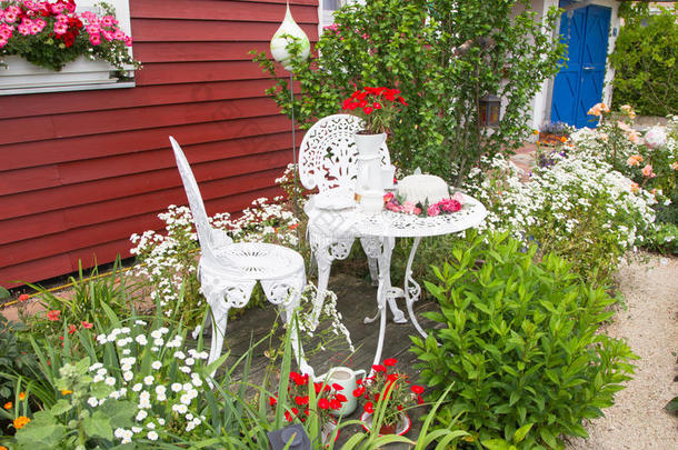乡间别墅前摆放着鲜花的花园家具。