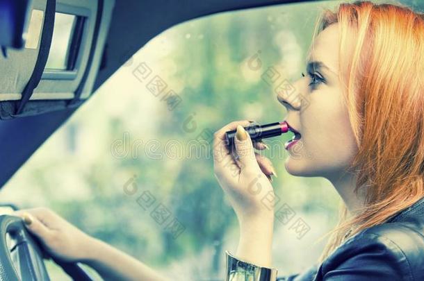 红发女人在嘴唇上涂唇膏。路上有危险。