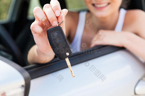 坐在车里拿钥匙的微笑的年轻女子