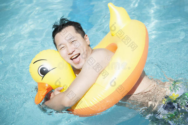 一个穿着黄鸭子充气管在游泳池里玩耍的男人
