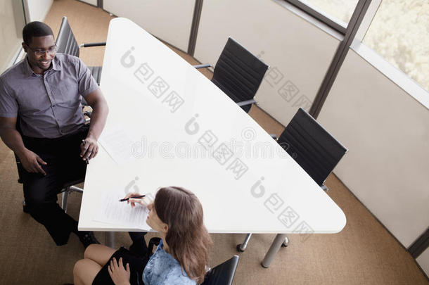 两个商务人士坐在会议桌旁，在商务会议上讨论