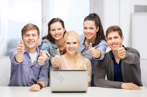 微笑的学生拿着笔记本电脑竖起大拇指