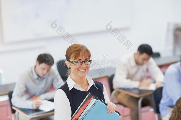 女老师在教室里摆姿势拿着一些文件