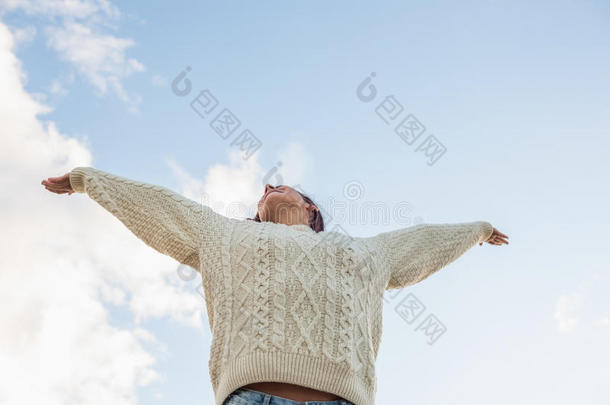 一个穿白毛衣的女人把胳膊伸向天空