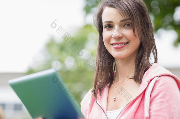 在户外使用平板电脑微笑的年轻女大学生