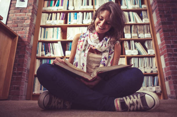 快乐女生靠着书架在图书馆地板上看书