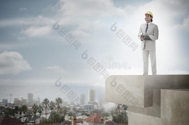 带着安全帽和写字板的建筑师对着天空和城市景观