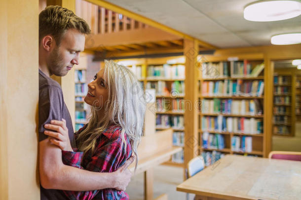 图书馆远处书架上的年轻浪漫夫妇
