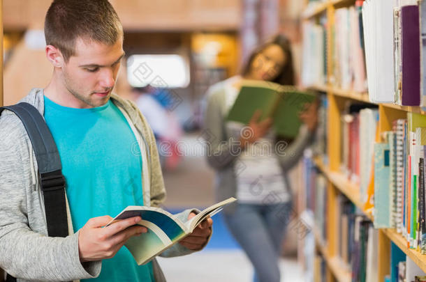 学生在图书馆书架旁看书