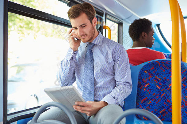 在<strong>公交车上</strong>使用手机和数字平板电脑的商人