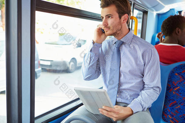 在公交车上使用手机和数字平板电脑的商人