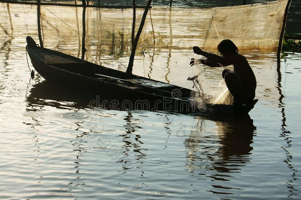 坐在划船上的渔夫，拿起渔网