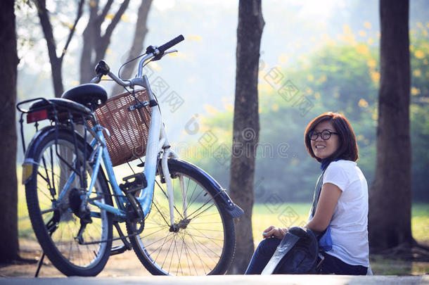 亚洲妇女早上骑自行车坐在公园里，在假日和度假中放松身心