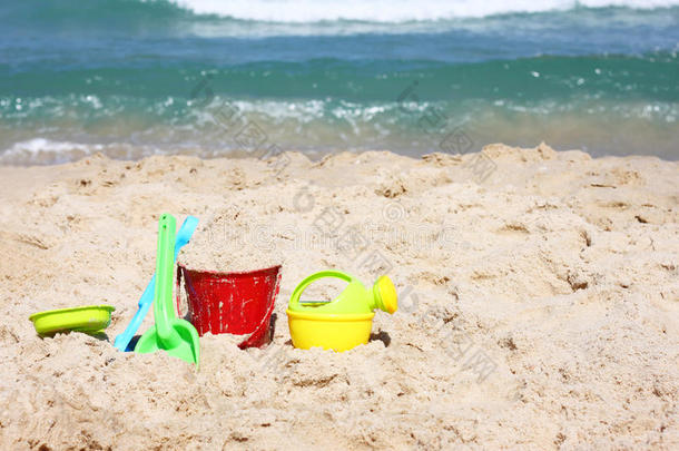 儿童沙滩玩具-阳光明媚的沙滩上的桶、铲子和铲子