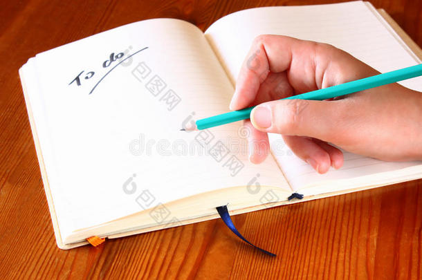 女人手里拿着铅笔，打开笔记本，上面有一张待办事项。