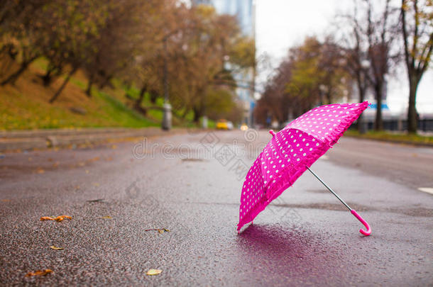湿沥青上的粉红色儿童伞