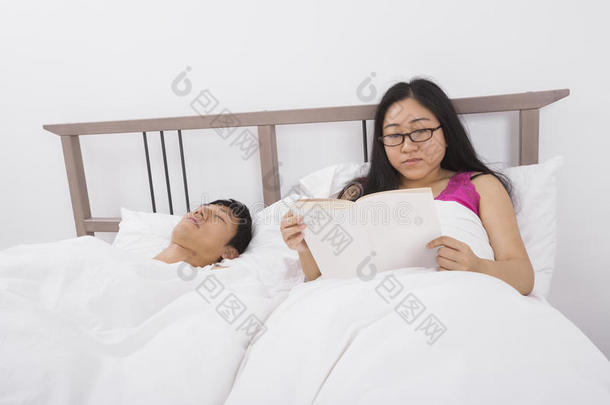 亚洲女青年卧床男子读书
