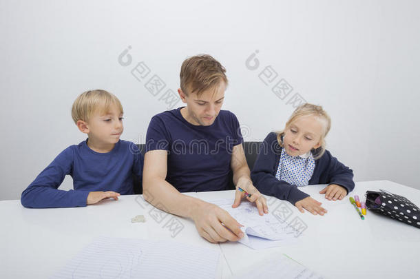 父亲在餐桌上检查孩子们的家庭作业