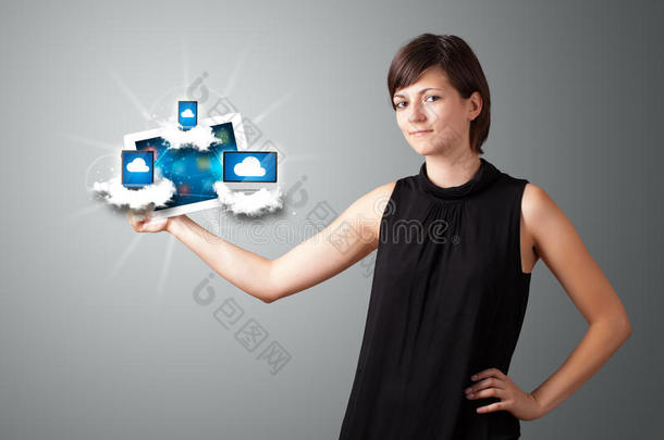 一个年轻的女人在云<strong>端</strong>拿着装有现代设备的平板<strong>电脑</strong>