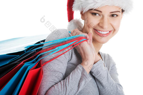 戴着圣诞帽，拎着购物袋的漂亮年轻女子。