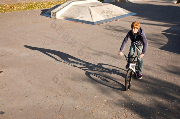 在溜冰场，一个红头发的男孩骑着他的bmx自行车跳跃