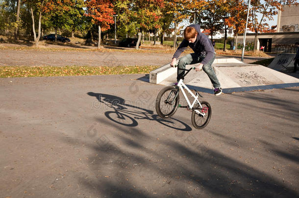 在溜冰场，一个红头发的男孩骑着他的bmx自行车跳跃