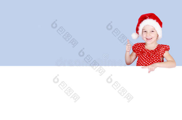 一个小女孩穿着红色的连衣裙，戴着圣诞老人的帽子，在广告牌上伸出一根手指