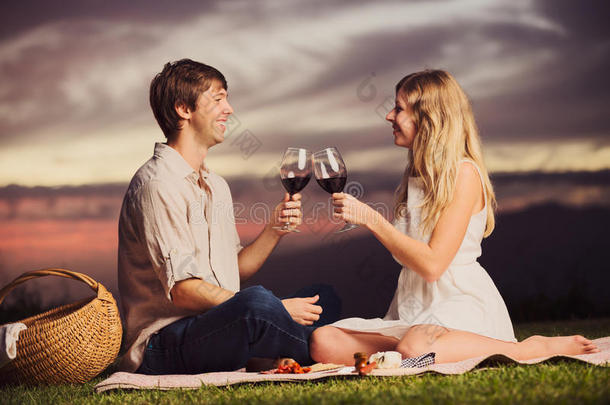 情侣们在浪漫的日落野餐上喝杯葡萄酒