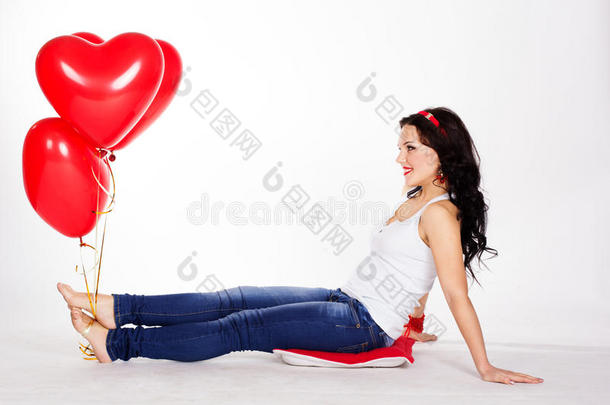 情人节美丽的年轻女子身穿红色连衣裙，手持红色气球