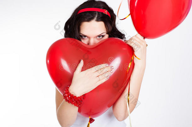 情人节美丽的年轻女子身穿红色连衣裙，手持红色气球