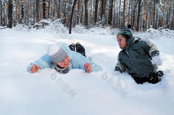 冬日的母亲带着儿子纵情地躺在森林里的雪地上