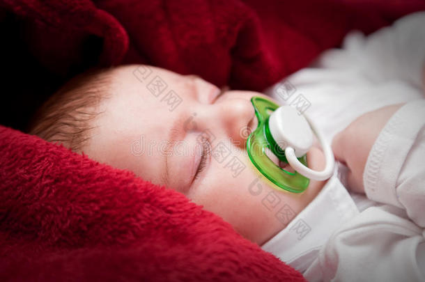 可爱的3个月大的婴儿，睡在铺着红毯子的床上