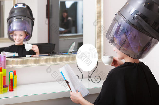 女客户卷发师看杂志美发美容院。