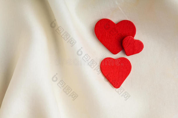 白色丝绸背景上的红色木质装饰心。