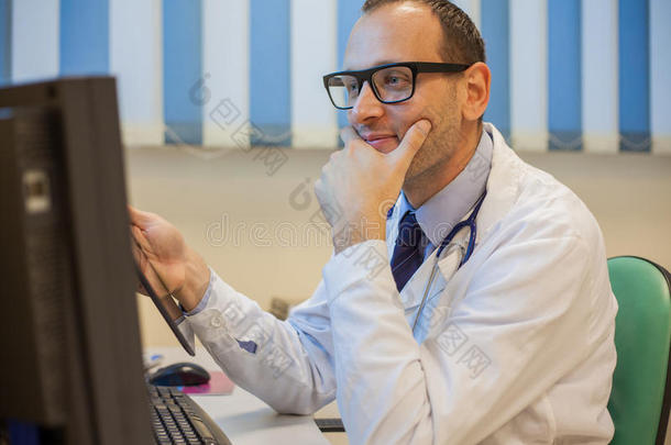 <strong>值班</strong>医生在他的办公室里用电脑和助听器工作