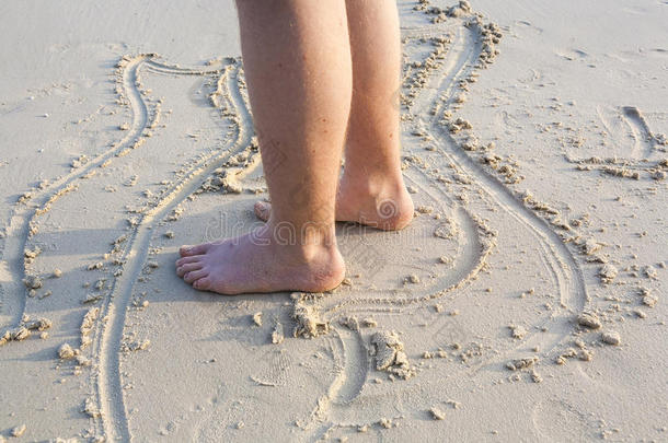 一个男孩的脚在细砂中画人物