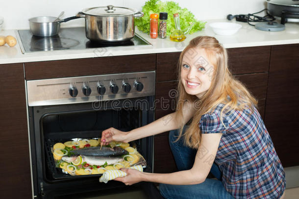 积极的女人在厨房的烤箱里<strong>煮鱼</strong>