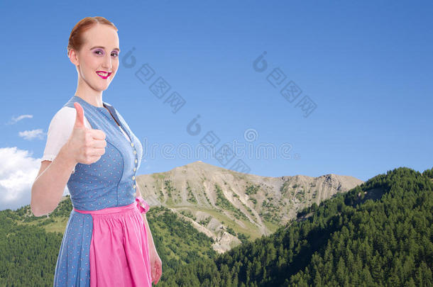 以拇指向上和蓝天为背景的巴伐利亚女孩