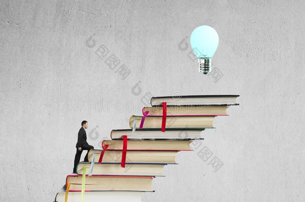 商人爬上一叠书，用灯泡达到顶峰