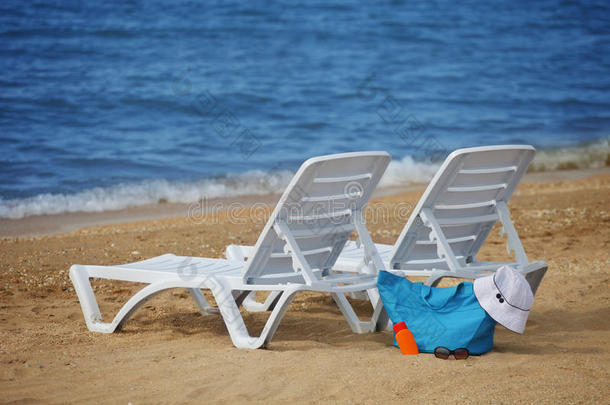 空沙滩上的躺椅和打包的沙滩包