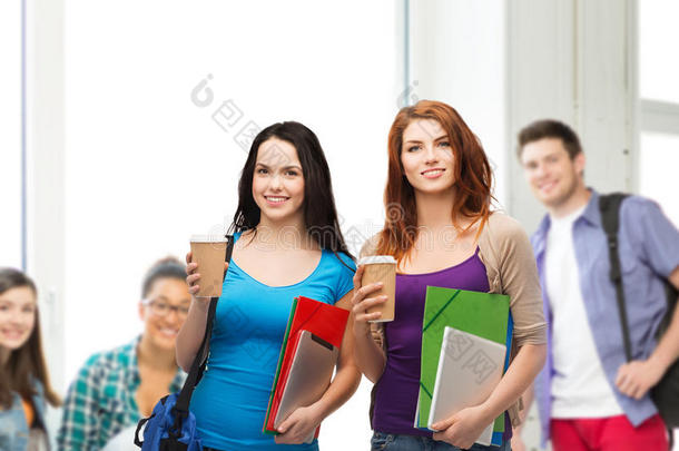 两个学生拿着包、文件夹、平板电脑和咖啡