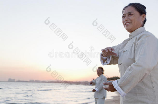 两位老人日落时在海滩上练习<strong>太极拳</strong>