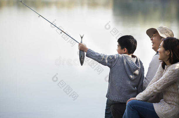 在湖边和家人一起垂钓的男孩