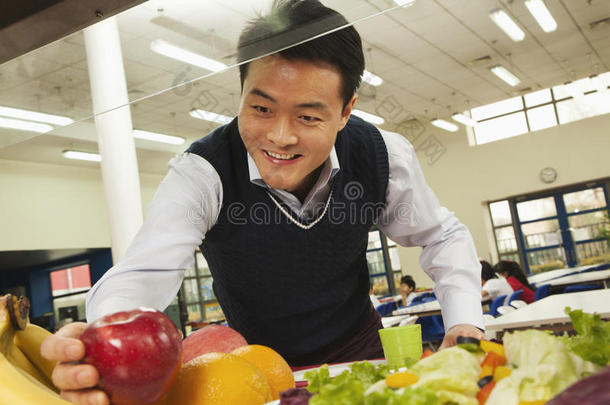 教师在学校食堂伸手取健康食品