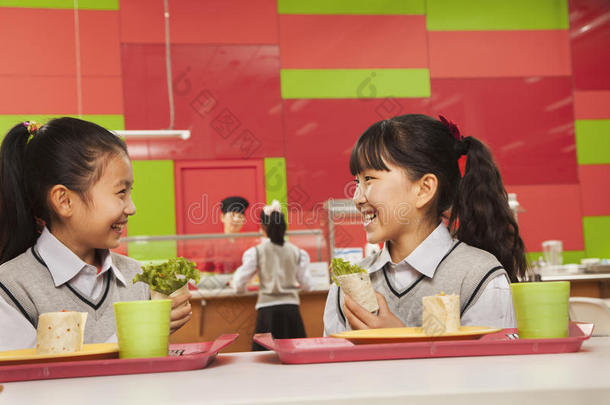 两个女孩在学校食堂午餐时聊天