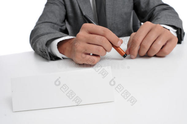 西装革履的男人坐在桌子上，前面有一块空白的招牌