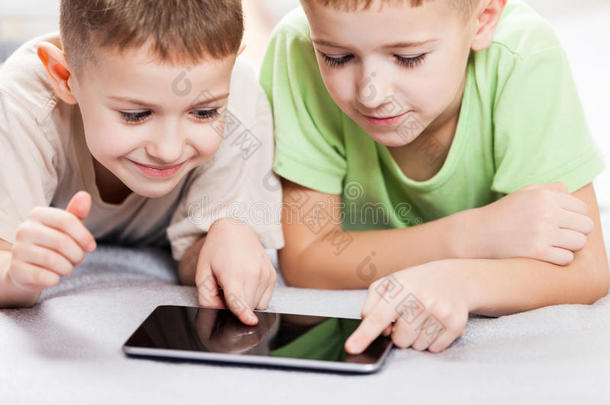 两个微笑的男孩在平板电脑上玩游戏或上网