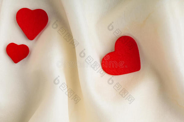 白色丝绸背景上的红色木质装饰心。